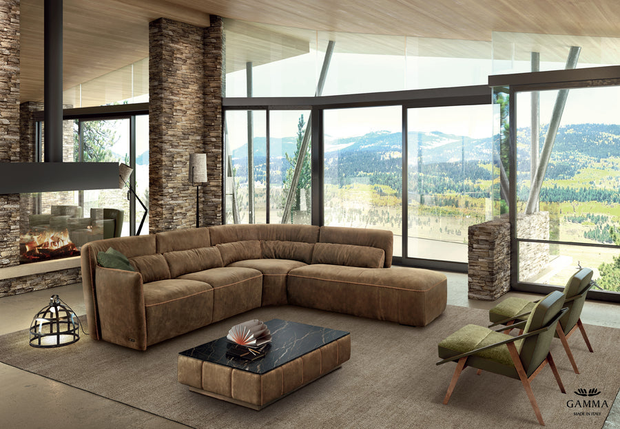 Brown leather Tulip sofa placed in a modern room with a fireplace and visible forest outside the window.