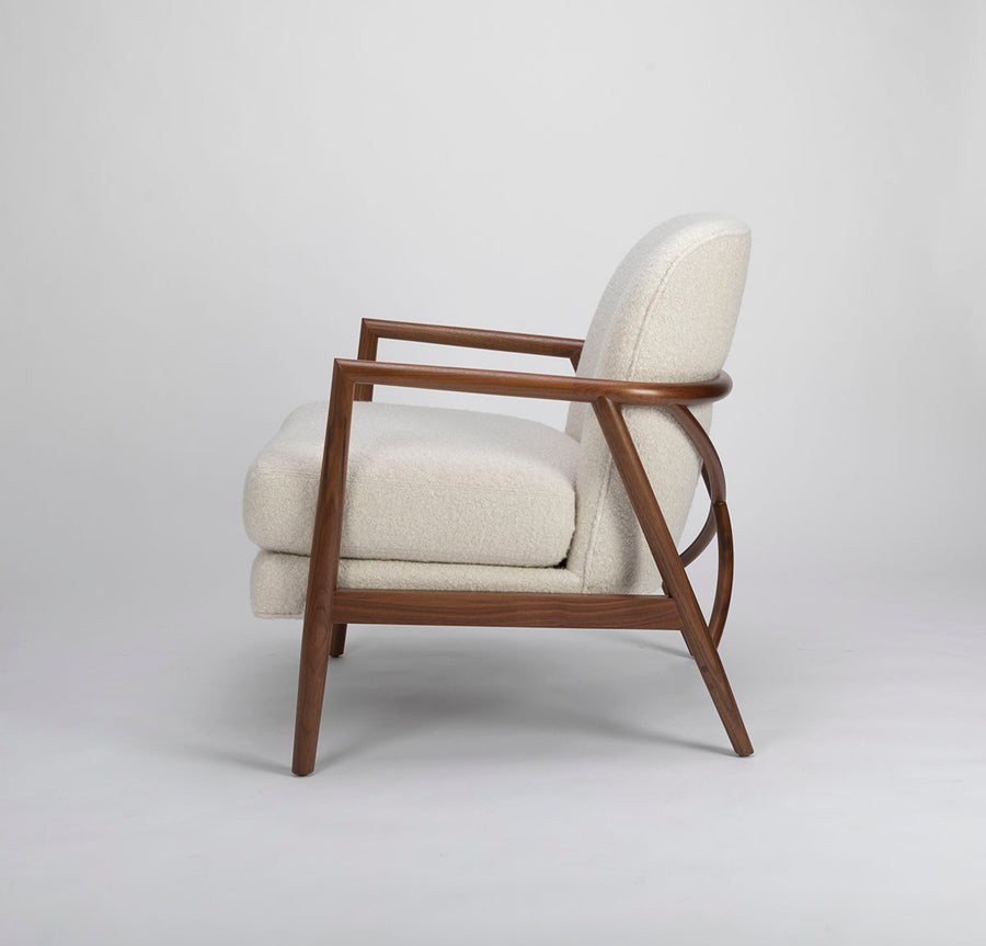 A white Lex lounge chair with solid maple frame, curved back. Side view.
