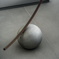 Elliptical modern Circle metal floor lamp done in dark brass with concrete ball base. Closed up view on ball base.
