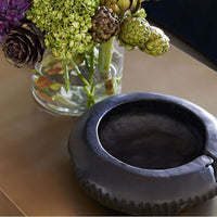 Erie Centerpiece Hand-carved of Natural Teak Root in Rich Ebony. Placed on a table with a vase with flowers.