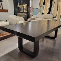 Oliver Dining Table with chamfered solid Ash base and strong top in dark walnut finish. Placed in a furniture store.