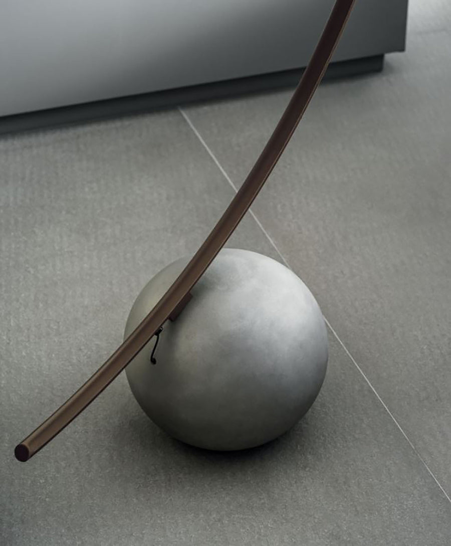 Elliptical modern Circle metal floor lamp done in dark brass with concrete ball base. Closed up view on ball base.