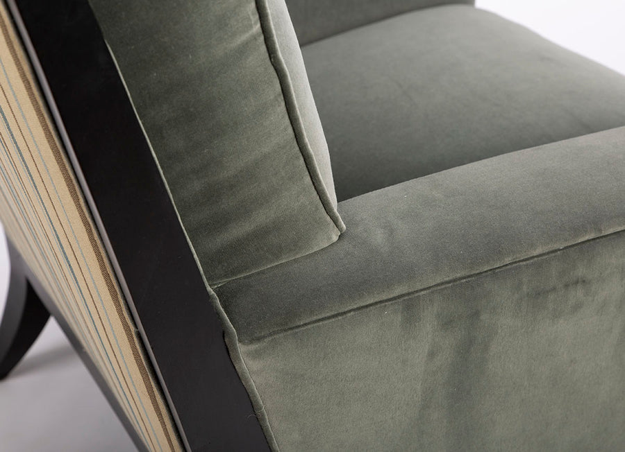 Curtis lounge chair in grey-green color with clean wood detail, softly splayed legs, and outside back framed by the wood trim, closed up side view.