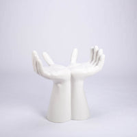 Sculptured stool that looks like two hands with opened palms for seating area made in white matte finish.