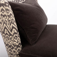 Beautifully shaped brown armless lounge chair with a curved back and seat rail, and saber shaped legs. Closed up side view.