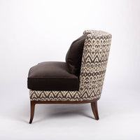 Beautifully shaped brown armless lounge chair with a curved back and seat rail, and saber shaped legs. Side view.