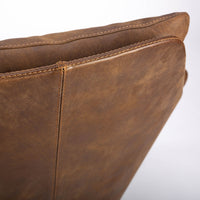 A brown modern and luxury leather armchair with glossy spoked base anchors. Closed up view.