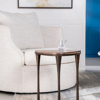 Reuleaux Drink Table placed in front of a white chair and with a glass on it.