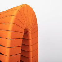 Orange and black Seat Belt dining chair with colorful seatbelt strappings, closed up top view.