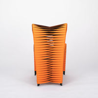 Orange and black Seat Belt dining chair with colorful seatbelt strappings, back view.