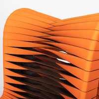 Orange and black Seat Belt dining chair with colorful seatbelt strappings, closed up top view.