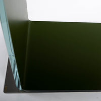 Two-toned bent glass coffee table with glued mat stainless steel plate. Closed up view on a steel plate.