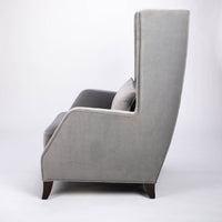 A light grey Rob lounge chair with extra high back, subtle angles and clean shape in the wing detail, side view.
