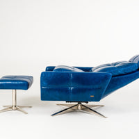 A reclined blue leather recliner chair with four star base and ottoman, side view.