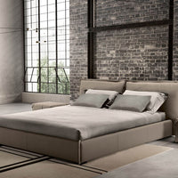 King Size Leather bed in grey color with a soft headboard, placed in a bricked wall room.