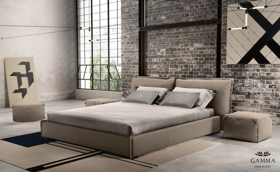 King Size Leather bed in grey color with a soft headboard, placed in a bricked wall room.