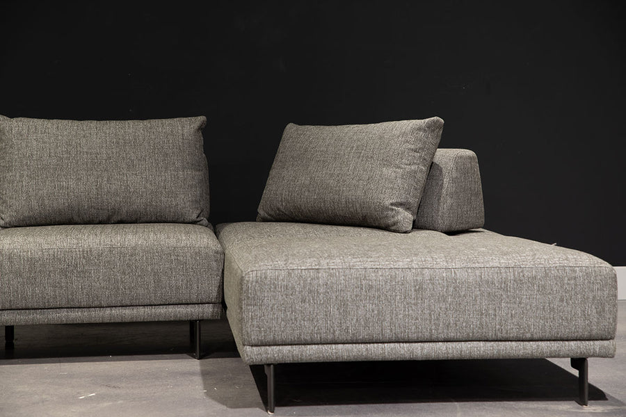 Grey fabric Felix Sectional with moveable back and arm rests and metal legs. Partial view of the right side.