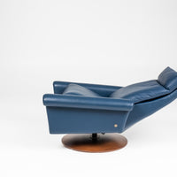 A blue leather Nimbus recliner chair with a disc base in Natural Walnut. Side view, reclined.