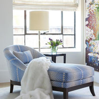 Lisette Chaise in light blue and white colors, placed in  a room with white blanket on it.
