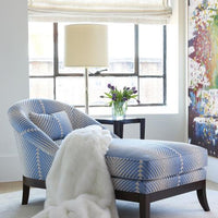 Lisette Chaise in light blue and white colors, placed in a room with white blanket on it.