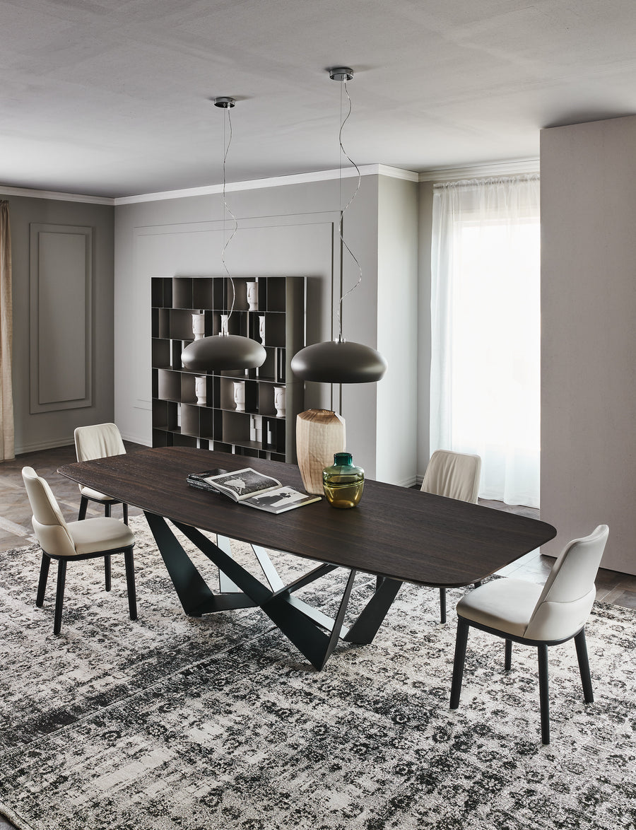 Wide Skorpio Dining Table with wooden top and origami based black base. Placed in a modern room with four white dining chairs.