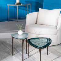 Two Reuleaux Drink Tables placed in front of a white chair and with a vase on one of them.