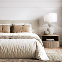 Eloise Table Lamp placed in a bedroom, next to a bed, on a round side table.