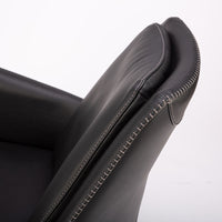 A black leather Kate swivel armchair. Closed up side view.