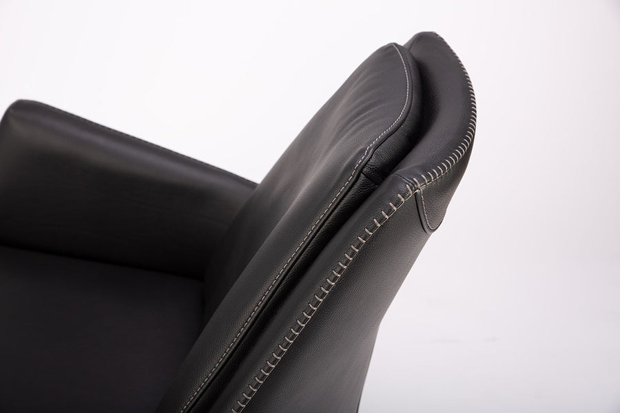 A black leather Kate swivel armchair. Closed up side view.