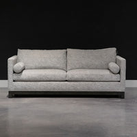 Grey two seat Oscar Sofa that features a slim tuxedo style, foam and down seats, arm bolsters and parson legs. Front view.