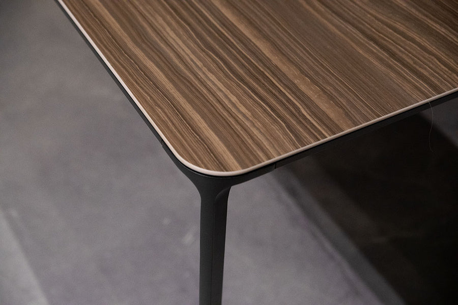 Slim Dining Table with die cast aluminum legs and wooden top. Closed up view on top surface.