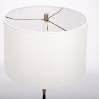 Morrison Lamp with a round Antique Brass base, white drum shade and candlestick silhouette body that combines Antique Brass with Matte Black. Closed up view on the shade.