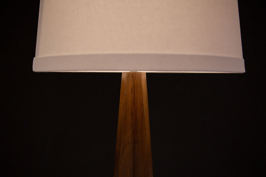 Linden Floor Lamp, a mid century adaptation with a tripod walnut base accented with brushed nickel foot caps and off white linen shade. Closed up view on the shade.