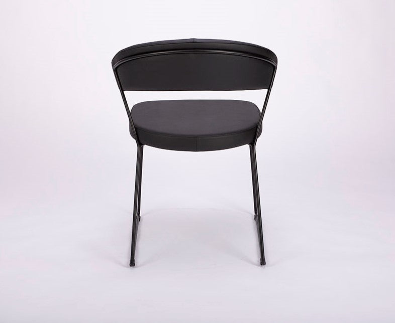 A black leather New York Dining Chair with metal frame and sled base and curved back. Back view.