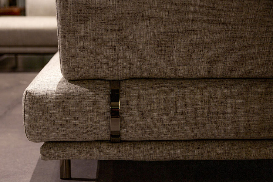 Light grey Quinta Strada Sectional with black chrome finish of the feet, the thinner joining clamps, and light base and back support. Closed up side view.