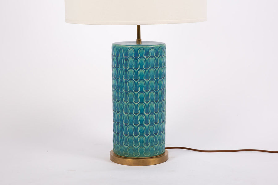 Eliot table lamp with white shade, blue & green wave pattern body with brass accents embellishing the base. Closed up view on the body and the base.