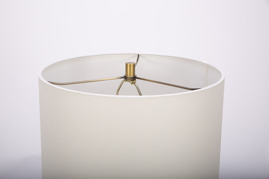 Gavin table lamp with a drum white shade and modern black ceramic body in an unique asymmetric design and a contrasting gold base. Closed up view on the base.