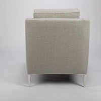 A light grey mid size lounge chair with classic shape and white legs. Back view.