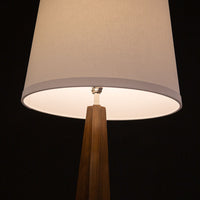 Linden Floor Lamp, a mid century adaptation with a tripod walnut base accented with brushed nickel foot caps and off white linen shade. Closed up view on the shade.