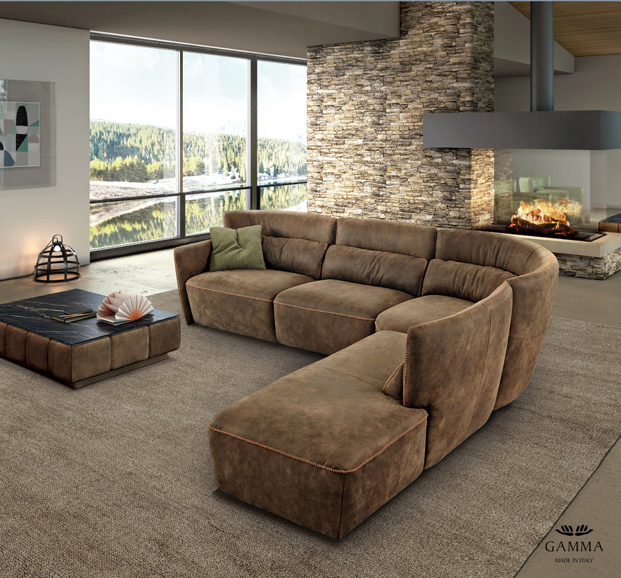 Brown leather Tulip sofa placed in a modern room with a fireplace and visible lake outside the window.
