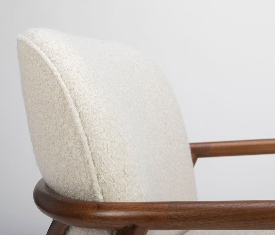 A white Lex lounge chair with solid maple frame, curved back. Closed up side view.