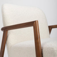 A white Lex lounge chair with solid maple frame, curved back. Closed up side view.