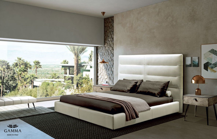 Sayonara leather bed in light colors with high headboard, placed with side tables in a modern room with a great view.