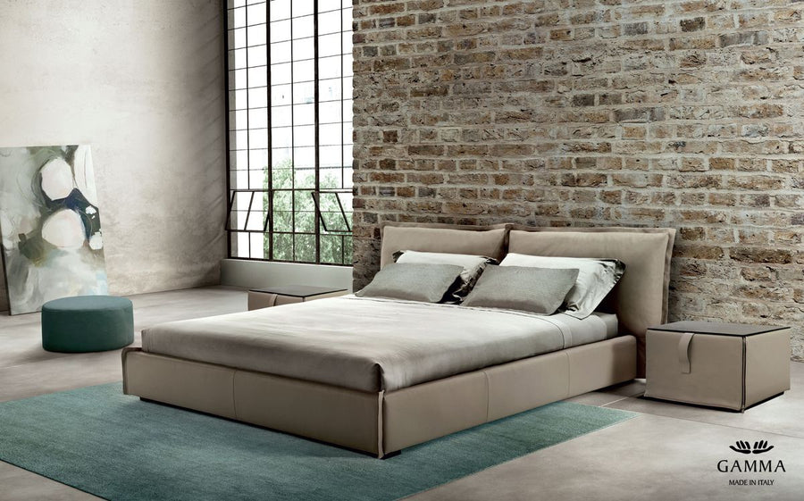 King Size Leather bed in grey color with a soft headboard, placed in a bricked wall room.