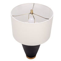 Gavin table lamp with a drum white shade and modern black ceramic body in an unique asymmetric design and a contrasting gold base. Closed up top view.