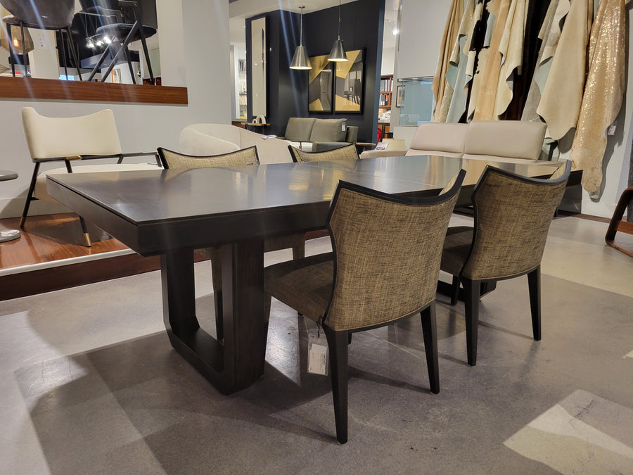 Oliver Dining Table with chamfered solid Ash base and strong top in dark walnut finish. Placed in a furniture store with four dining chair around it.
