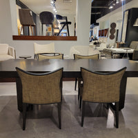 Oliver Dining Table with chamfered solid Ash base and strong top in dark walnut finish. Placed in a furniture store with four dining chairs around it.