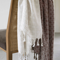 A white and a brown Caldwell Plaster Throw Blanket hanging on a chair.