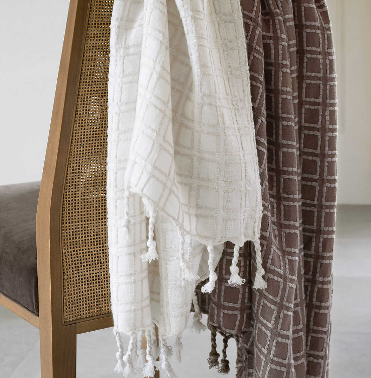 A white and a brown Caldwell Plaster Throw Blanket hanging on a chair.