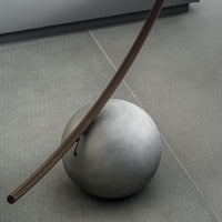 Elliptical modern Circle metal floor lamp done in dark brass with concrete ball base. Closed up view on ball base.